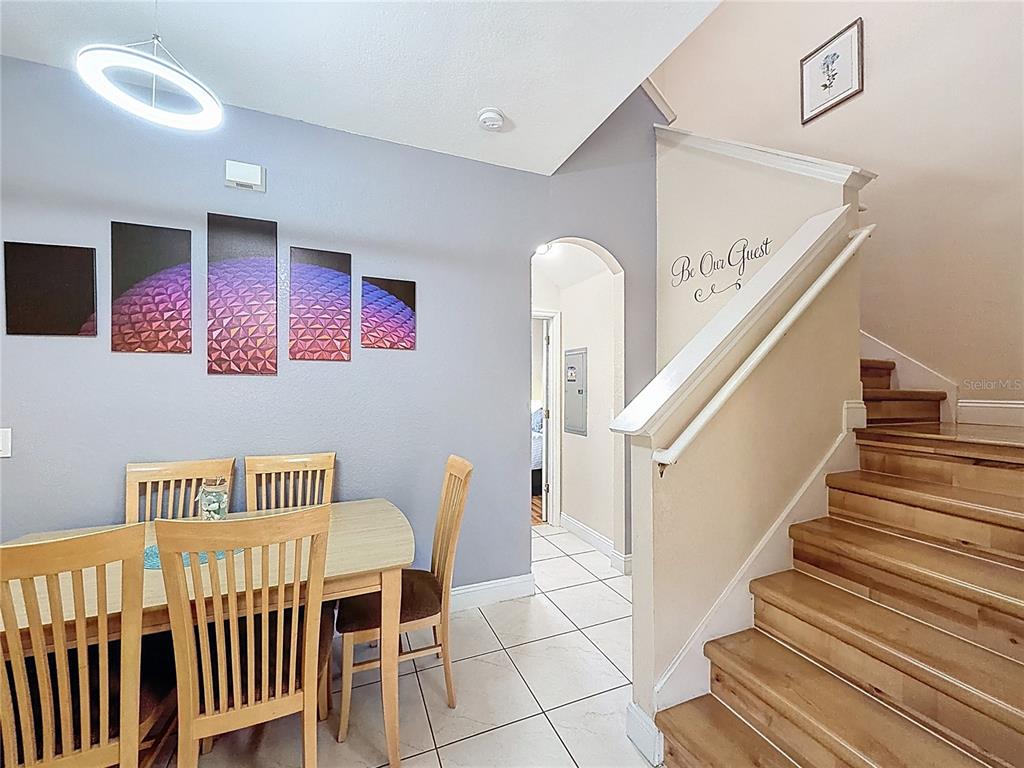 A dining area with a wooden table and chairs sits beside a staircase with wooden steps — 223 NAPOLI DRIVE, DAVENPORT, FL