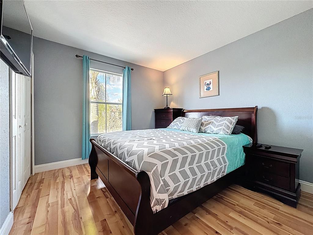 A bedroom features a dark wood sleigh bed, light blue walls, and hardwood flooring — 223 NAPOLI DRIVE, DAVENPORT, FL