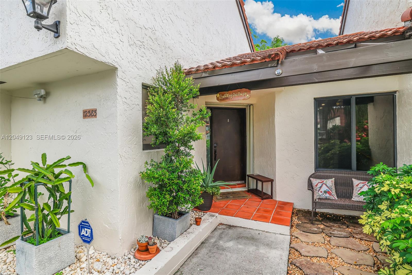 The exterior entrance features a tiled porch, a dark wooden door, and potted plants — 12383 SW 94th Ter, Miami FL 33186, MIAMI, FL