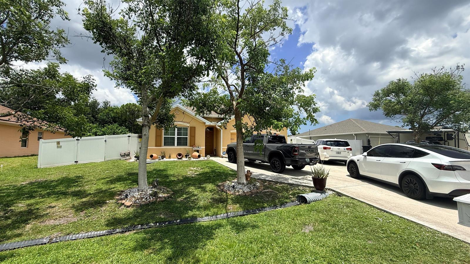 A single-story house with a driveway, two parked vehicles, and two trees in the yard — 2369 SW Barber Lane, Port St. Lucie FL 34984, PORT ST. LUCIE, FL