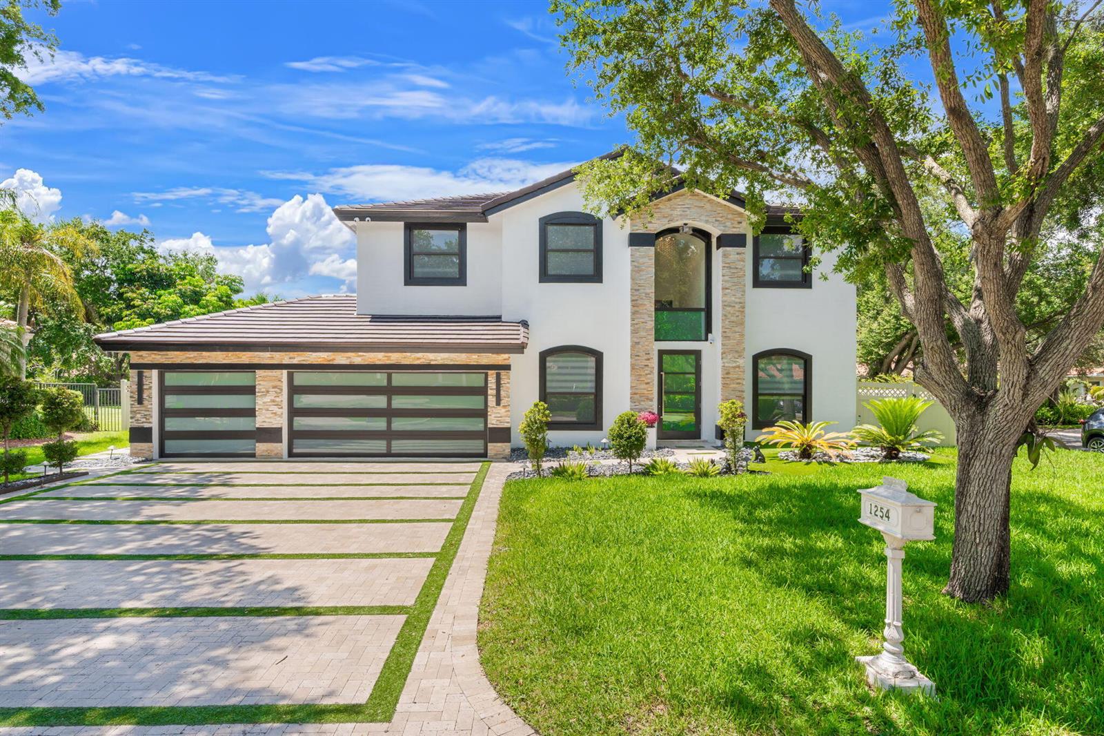 A two-story white house with a stone facade, dark-framed windows, and a modern garage — 1254 NW 102nd Way, Coral Springs FL 33071, CORAL SPRINGS, FL
