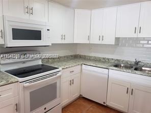 A kitchen features white cabinets, granite countertops, a white microwave, and a white electric range — 20 NW 87th Ave # A214, Miami FL 33172, MIAMI, FL