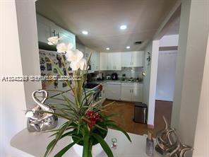 A kitchen with white cabinets and a counter featuring a decorative plant in the foreground — 20 NW 87th Ave # A214, Miami FL 33172, MIAMI, FL