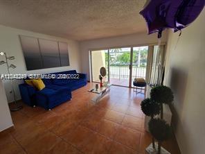 A living room features a blue sectional sofa, tile flooring, and a sliding glass door — 20 NW 87th Ave # A214, Miami FL 33172, MIAMI, FL