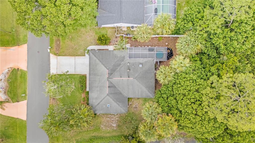 An aerial view shows a house with a gray roof, a screened-in patio, and landscaping — 19 BANNER LANE, PALM COAST, FL