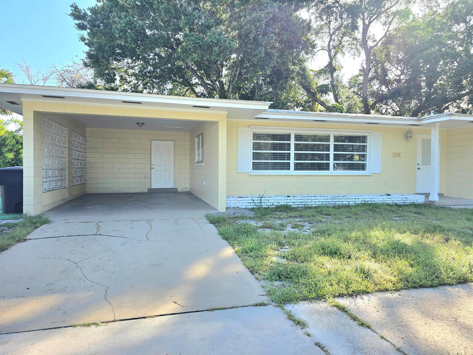 A single-story yellow house with a carport, a large front window, and a concrete driveway — 580 Wendell Road, Fort Pierce FL 34950, FORT PIERCE, FL