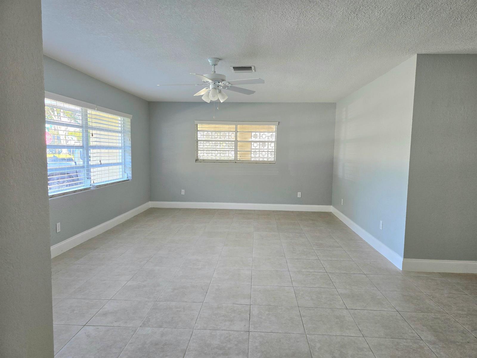 An empty room with light gray walls, tile flooring, a ceiling fan, and two windows — 580 Wendell Road, Fort Pierce FL 34950, FORT PIERCE, FL