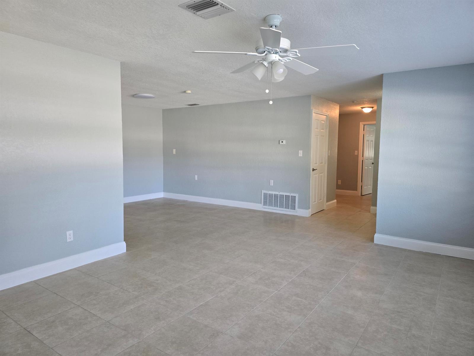 An empty room with light gray walls, tile flooring, and a white ceiling fan — 580 Wendell Road, Fort Pierce FL 34950, FORT PIERCE, FL