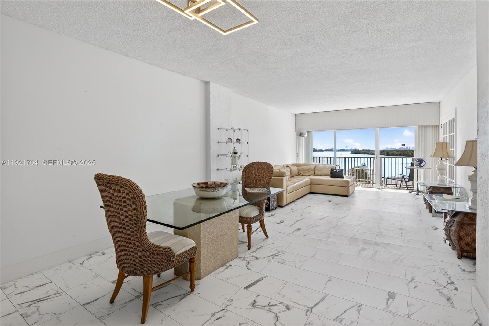 An empty room features white marble-look tile floors, a modern light fixture, and a balcony — 300 Bayview Dr # 308, Sunny Isles Beach FL 33160, SUNNY ISLES BEACH, FL