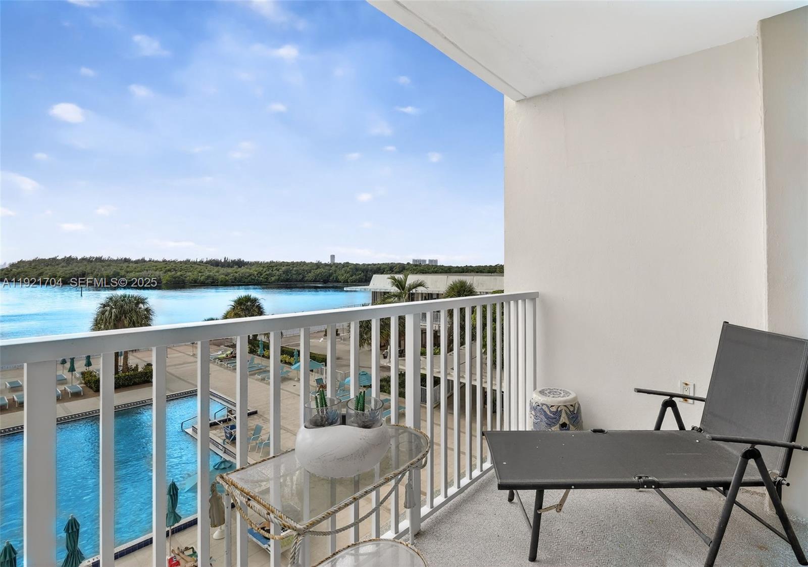 A balcony overlooks a swimming pool and a body of water under a blue sky — 300 Bayview Dr # 308, Sunny Isles Beach FL 33160, SUNNY ISLES BEACH, FL