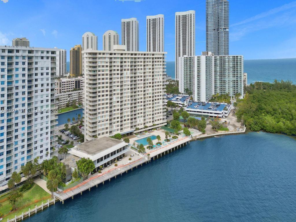 A bright, empty room features white marble-patterned tile floors, large sliding glass doors, and a kitchen — 300 Bayview Dr # 308, Sunny Isles Beach FL 33160, SUNNY ISLES BEACH, FL