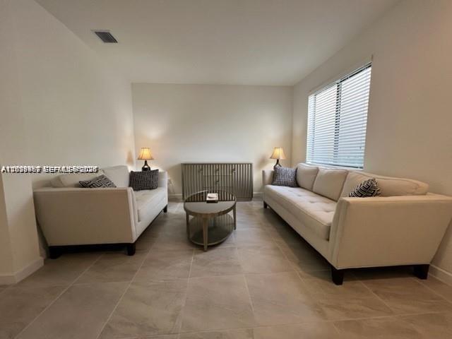 A living room features two white sofas, a central coffee table, and a wooden console — 327 NE 208th Ter, Miami FL 33179, MIAMI, FL