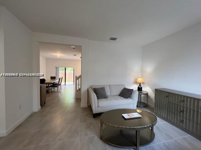 A living room with a white sofa, round coffee table, and a wooden sideboard — 327 NE 208th Ter, Miami FL 33179, MIAMI, FL