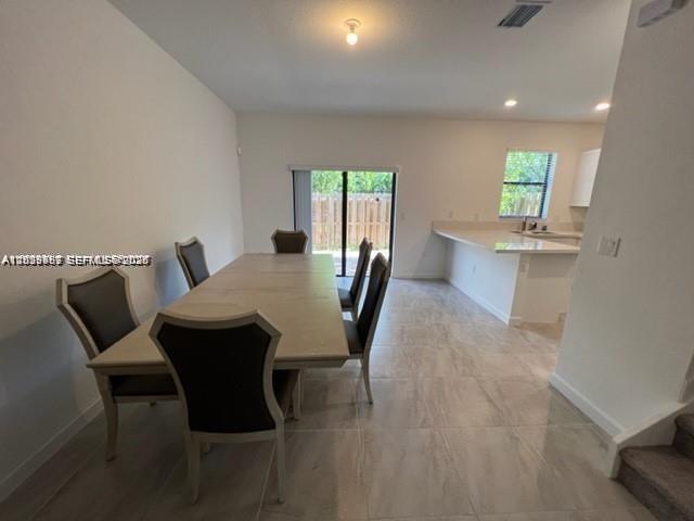 A dining area with a table and chairs sits adjacent to an open kitchen — 327 NE 208th Ter, Miami FL 33179, MIAMI, FL