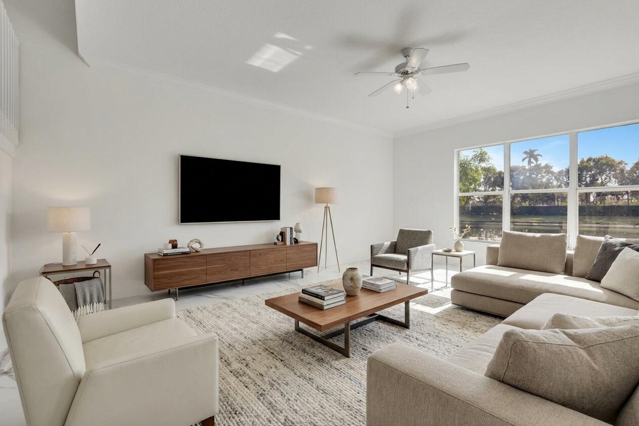 A bright living room features a large sectional sofa, wooden media console, and floor-to-ceiling windows — 9334 Madewood Court, Royal Palm Beach FL 33411, ROYAL PALM BEACH, FL