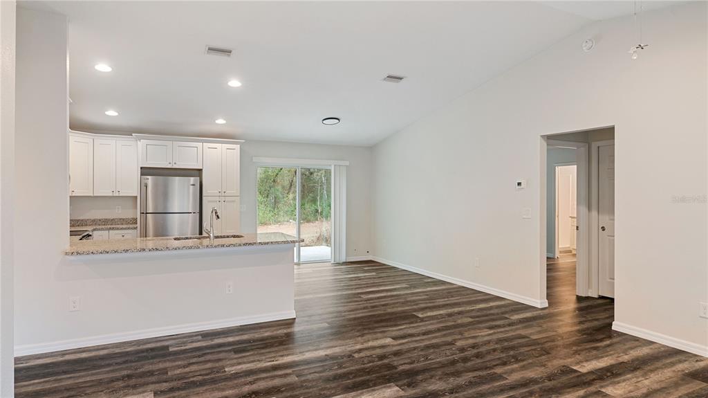 A kitchen with white cabinets and stainless steel appliances overlooks an open living area — 296 OAK LANE TRACK, OCALA, FL