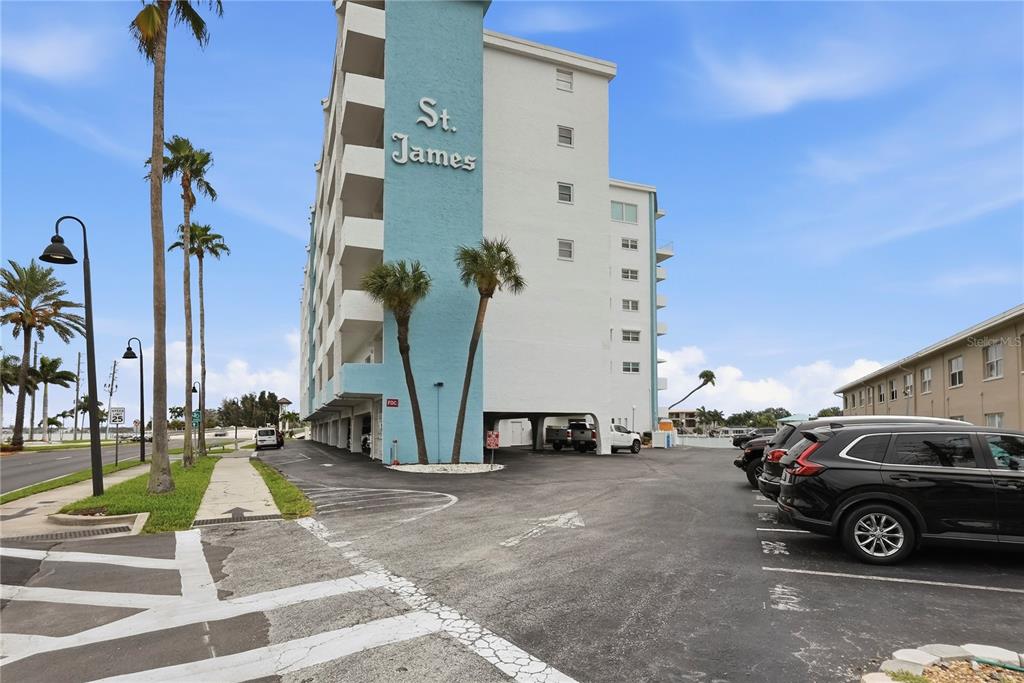 The exterior of a multi-story apartment building features a parking lot and palm trees — 285 107TH AVENUE UNIT 405, ST PETERSBURG, FL