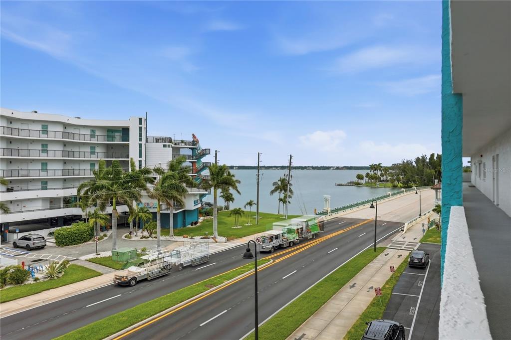 An elevated view shows a road, a waterfront building, and a bridge under a blue sky — 285 107TH AVENUE UNIT 405, ST PETERSBURG, FL