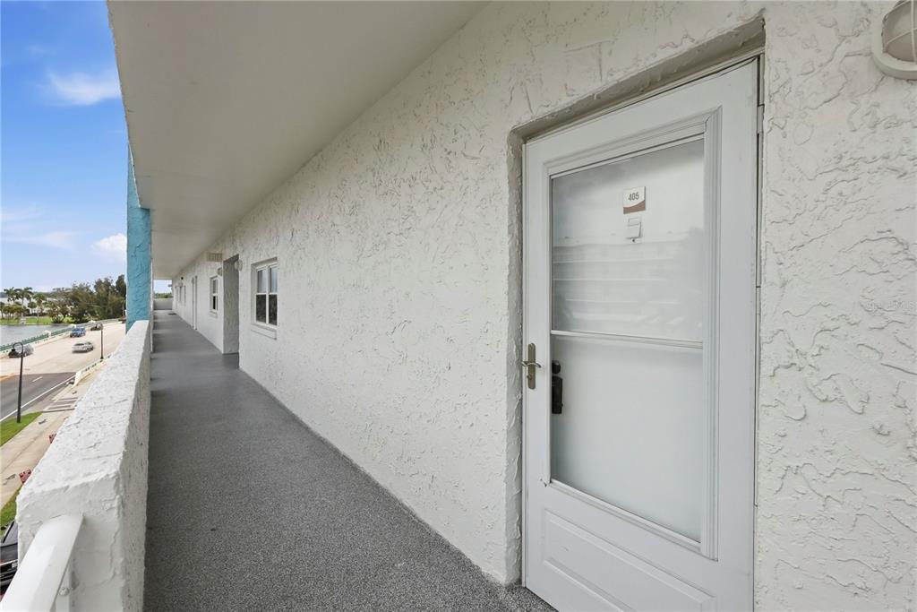 An exterior walkway with white stucco walls and a white door labeled 405 — 285 107TH AVENUE UNIT 405, ST PETERSBURG, FL