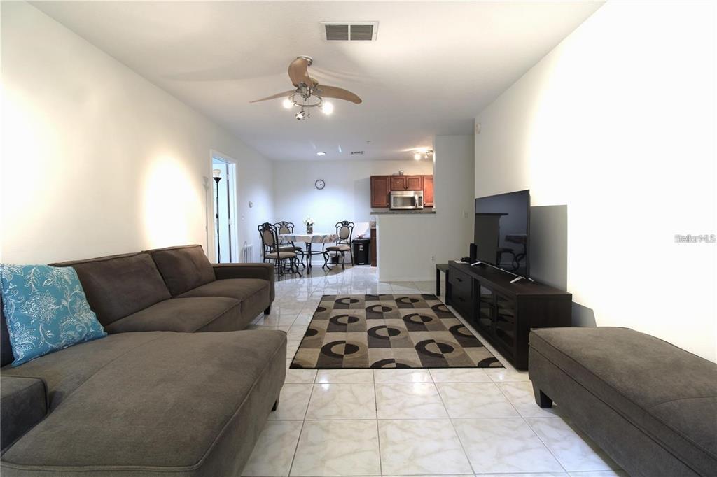 A living room with tile floors, a brown sectional sofa, and an adjacent dining area — 4320 S KIRKMAN ROAD UNIT 1501, ORLANDO, FL