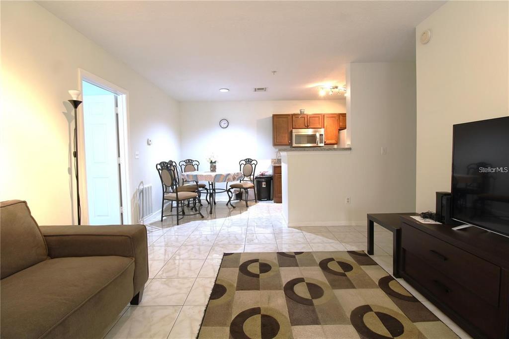 A living room with tile floors, a patterned rug, and an adjacent dining area and kitchen — 4320 S KIRKMAN ROAD UNIT 1501, ORLANDO, FL