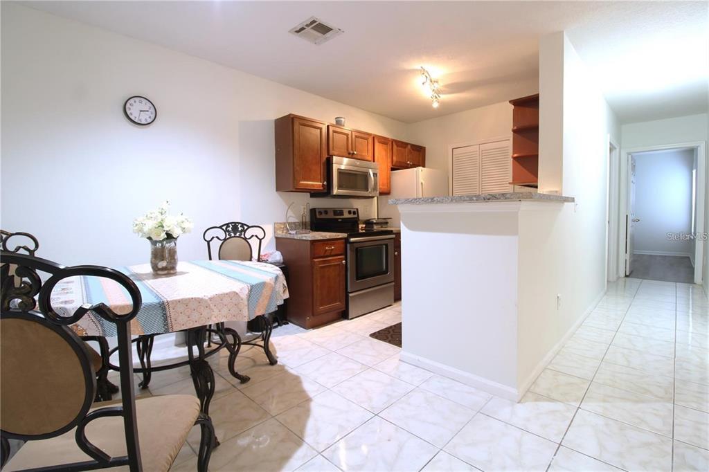A kitchen with wood cabinets and stainless steel appliances sits next to a dining area — 4320 S KIRKMAN ROAD UNIT 1501, ORLANDO, FL
