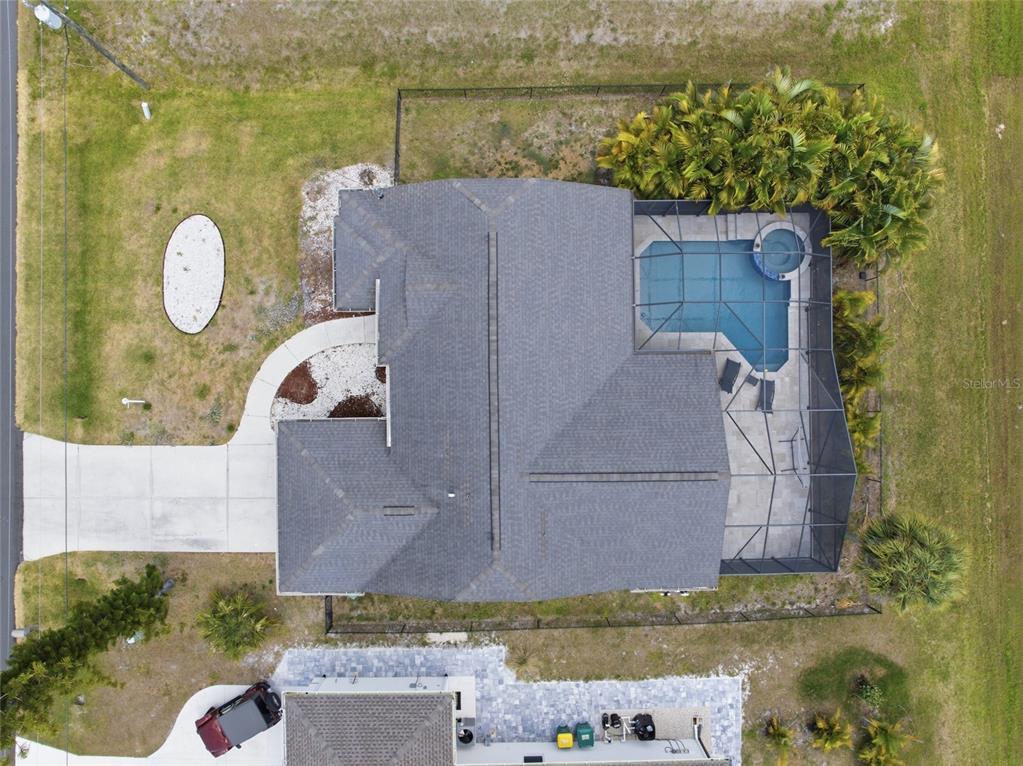 An aerial view shows a house with a shingled roof, pool, and screened-in patio — 257 BROADMOOR LANE, ROTONDA WEST, FL