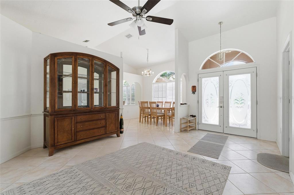 A bright entryway features tile flooring, a large wooden hutch, and a dining area beyond — 257 BROADMOOR LANE, ROTONDA WEST, FL