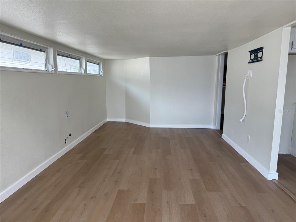 An empty room features light wood-look flooring, white walls, and three horizontal windows — 2601 GULF DRIVE N UNIT 506, BRADENTON BEACH, FL