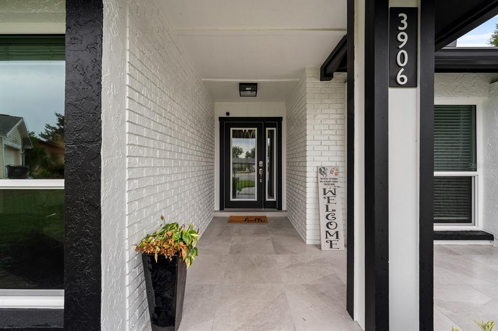 A covered entryway features white painted brick walls, a black front door, and large floor tiles — 3906 BRAUN WAY, VALRICO, FL
