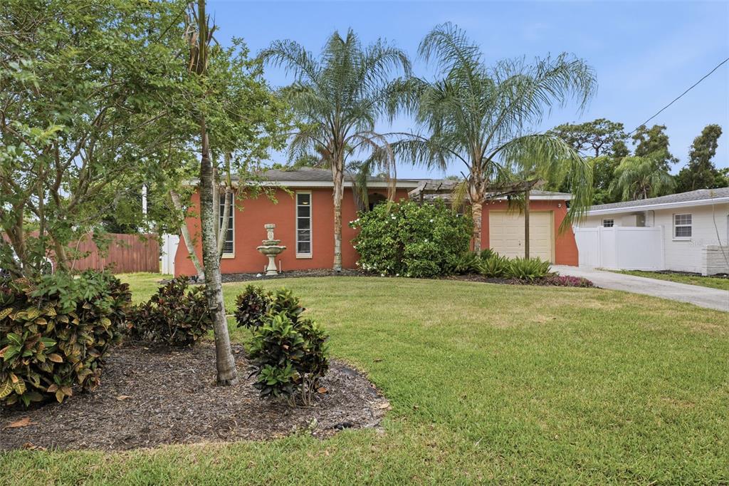 A single-story house with a terracotta-colored exterior, a front fountain, and two palm trees — 51 CYPRESS DRIVE, PALM HARBOR, FL