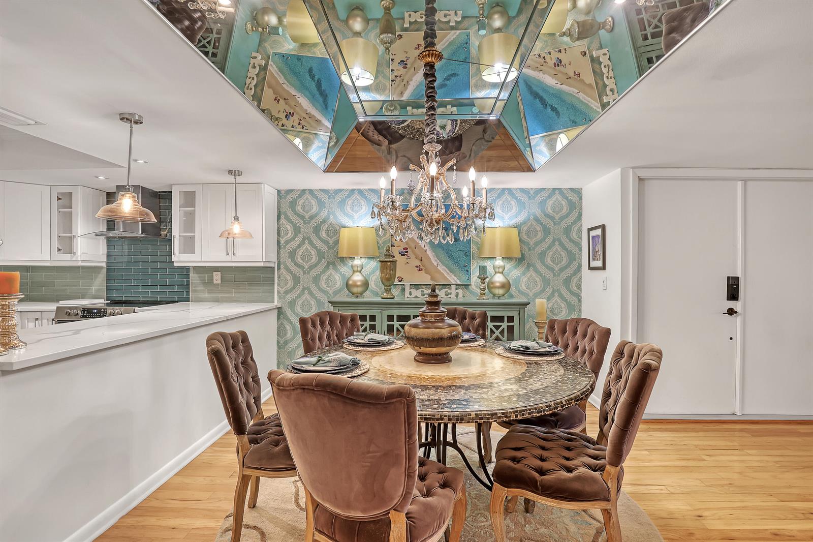 A dining room features a round table, tufted chairs, a chandelier, and a mirrored ceiling — 1100 Surf Road # 104, Singer Island FL 33404, SINGER ISLAND, FL