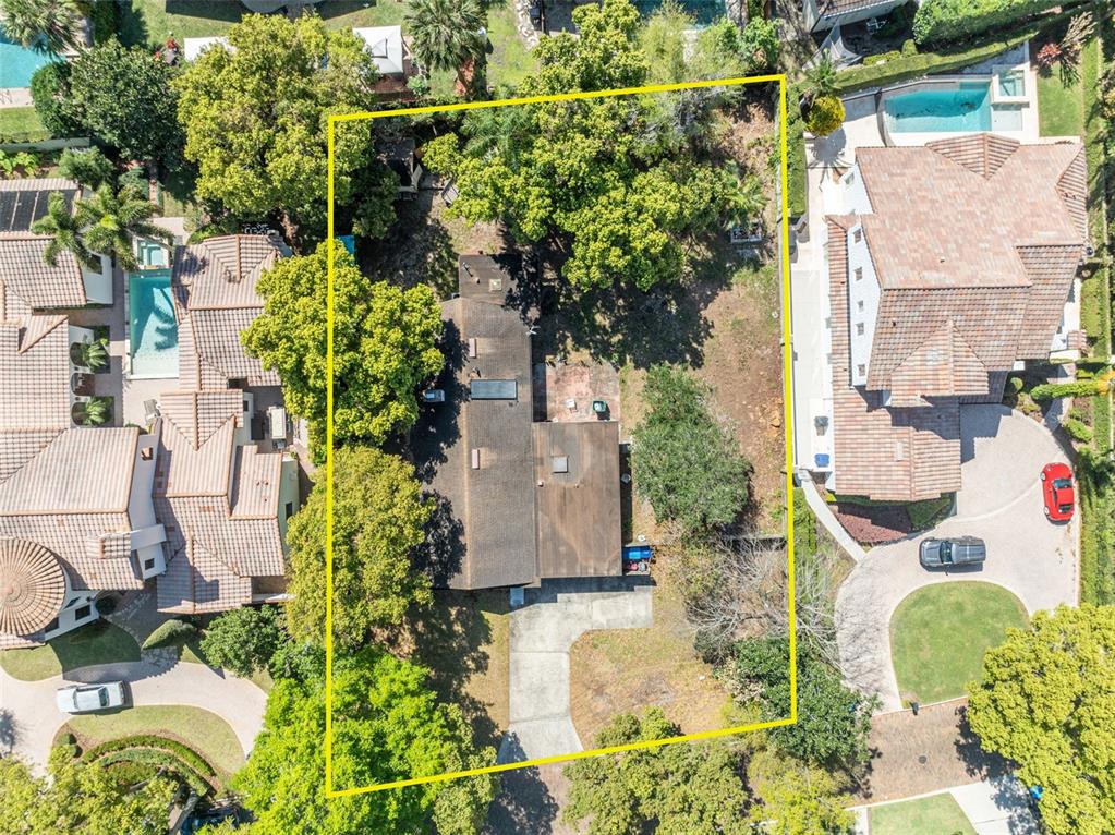 A mid-century modern house with a carport sits behind a brick street and trees — 1560 LAKEHURST AVENUE, WINTER PARK, FL