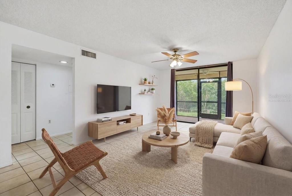 This living room features a television, a sofa, a coffee table, and a ceiling fan — 1332 PASADENA UNIT 102, SOUTH PASADENA, FL