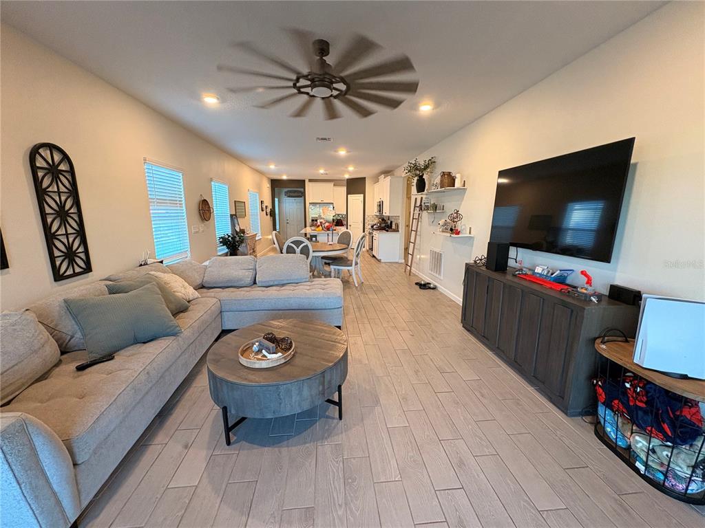 A living room with a sectional sofa, coffee table, and television opens into a kitchen — 1525 NW 44TH COURT ROAD, OCALA, FL