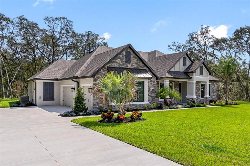 A single-story house features a stone facade, a multi-car garage, and a landscaped front lawn — 13704 OLDENBURG DRIVE, HUDSON, FL
