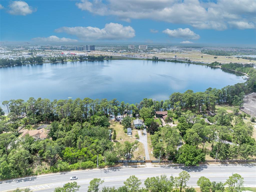 An aerial view shows a lakefront property with a house, trees, and a nearby road — 11424 WESTWOOD BOULEVARD, ORLANDO, FL
