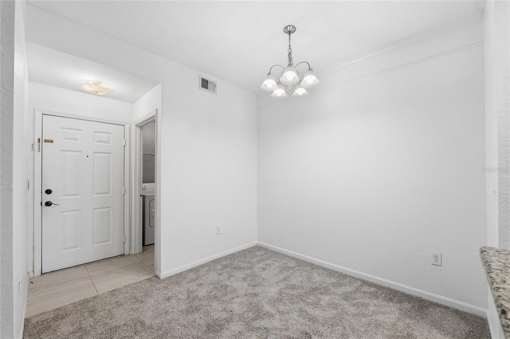 A dining area with gray carpet, a white door, and a hanging chandelier — 17112 CARRINGTON PARK DRIVE UNIT 926, TAMPA, FL