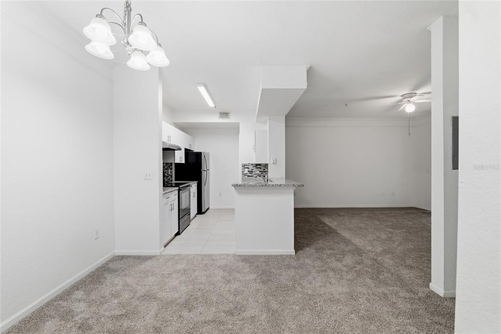 A dining area with a chandelier opens to a kitchen and a carpeted living space — 17112 CARRINGTON PARK DRIVE UNIT 926, TAMPA, FL