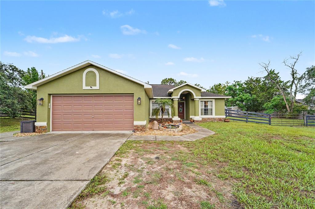 A single-story house with a green exterior, a two-car garage, and a front walkway — 13466 NEVILLE DRIVE, SPRING HILL, FL