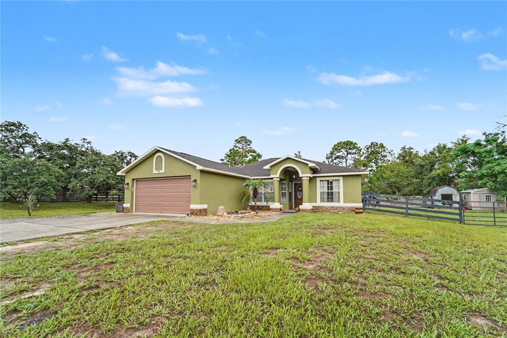 A single-story house with a green exterior, a two-car garage, and a fenced yard — 13466 NEVILLE DRIVE, SPRING HILL, FL