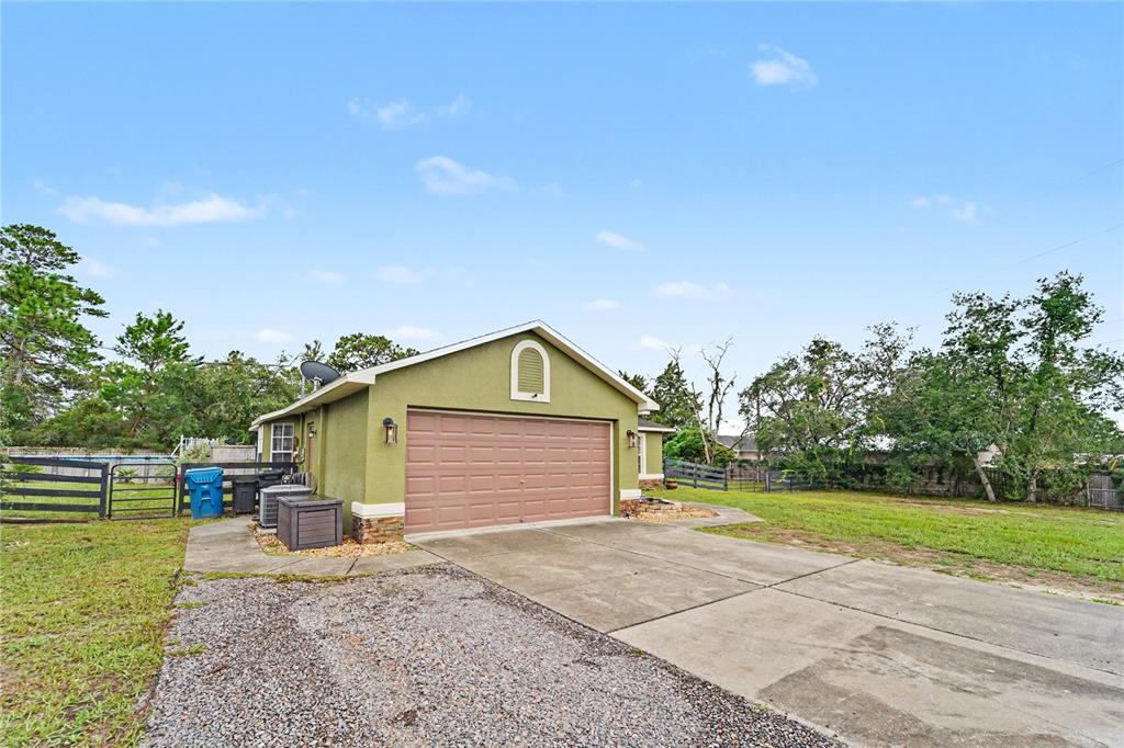 A detached garage with a brown door sits on a concrete driveway in a yard — 13466 NEVILLE DRIVE, SPRING HILL, FL