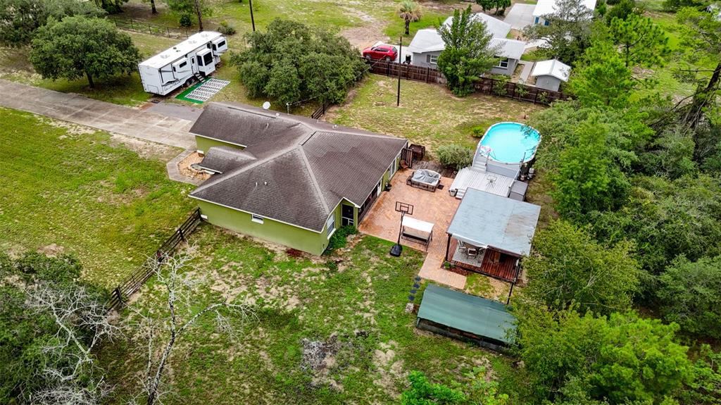 An aerial view shows a house with a pool, patio, and RV on a grassy lot — 13466 NEVILLE DRIVE, SPRING HILL, FL