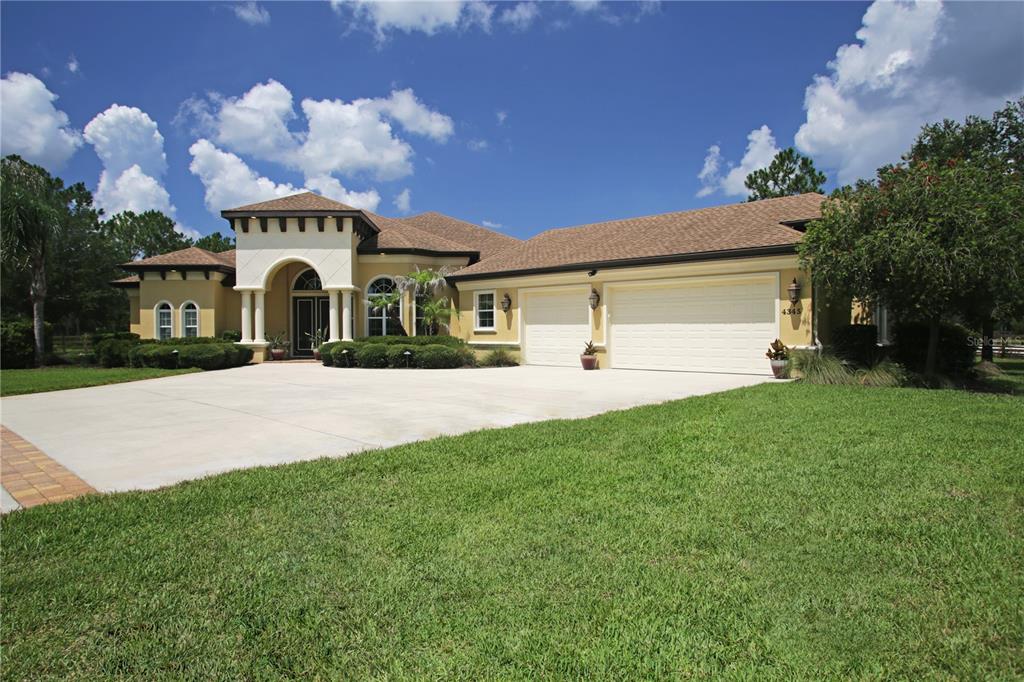 A single-story house with a beige stucco exterior, a three-car garage, and a concrete driveway — 4345 OLD KINGS ROAD N, PALM COAST, FL