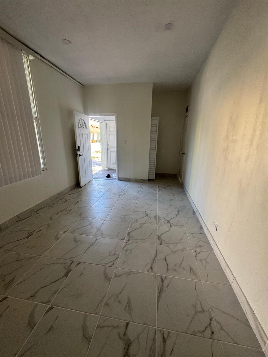An empty room with white walls, marble-patterned tile flooring, and an open door to outside — 804 Orange Avenue # B, Fort Pierce FL 34950, FORT PIERCE, FL
