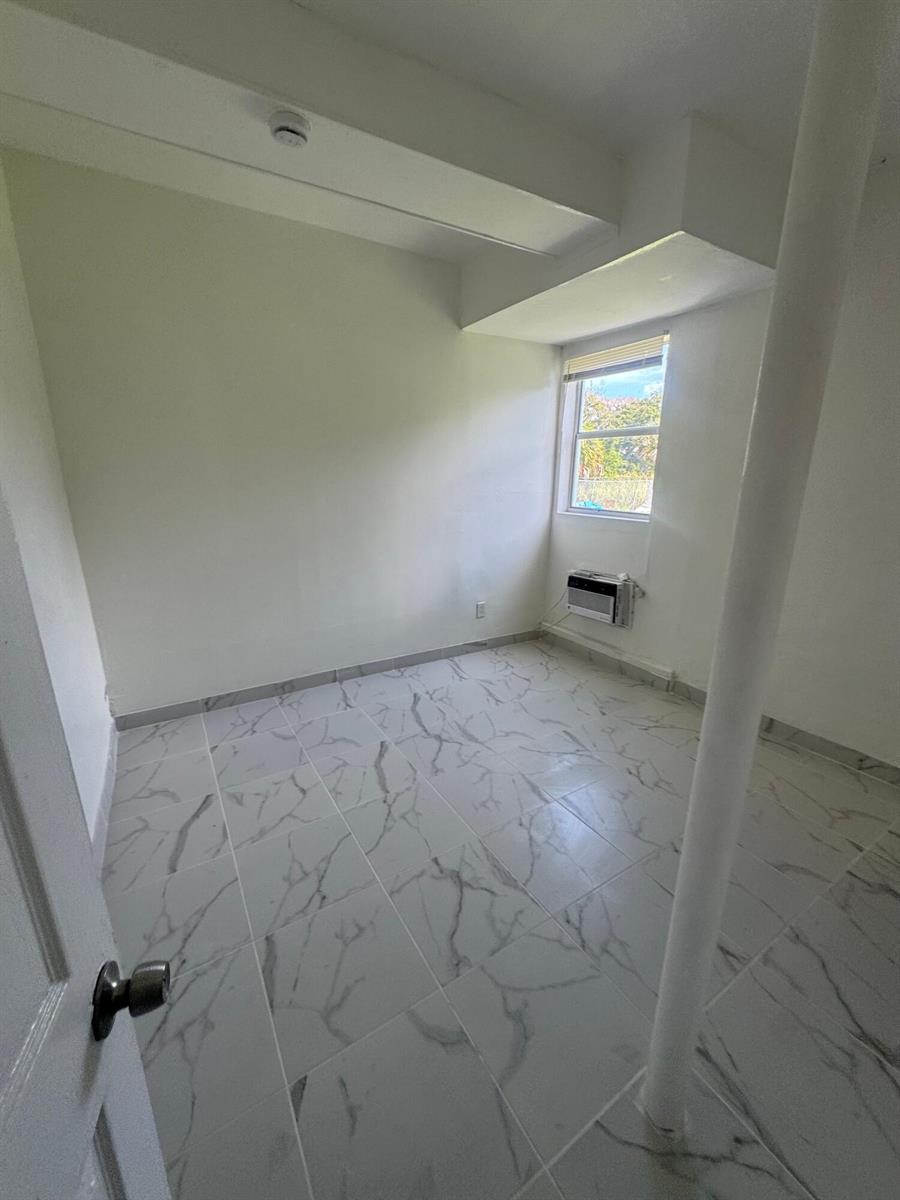 A small room with white walls, white marble-patterned tile flooring, and a window air conditioner — 804 Orange Avenue # B, Fort Pierce FL 34950, FORT PIERCE, FL
