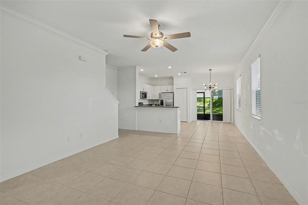 An open-concept living and dining area features white walls, tile flooring, and a kitchen — 36456 WELL HILL WAY, ZEPHYRHILLS, FL