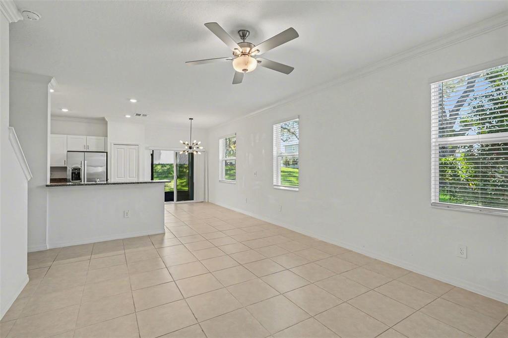 An open-concept living and dining area features white walls, tile flooring, and a ceiling fan — 36456 WELL HILL WAY, ZEPHYRHILLS, FL
