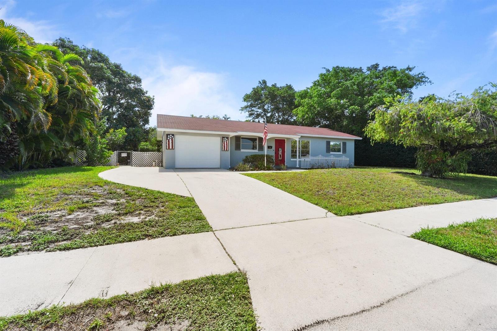 A single-story house with a white garage, red front door, and a concrete driveway — 1515 CRESCENT Drive, Lake Park FL 33403, LAKE PARK, FL