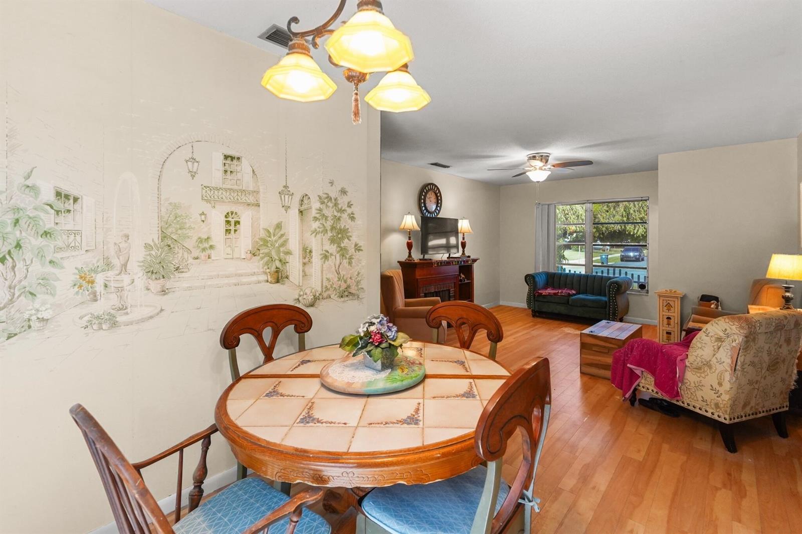 A dining area with a mural wall and a round table opens into a living room — 1515 CRESCENT Drive, Lake Park FL 33403, LAKE PARK, FL